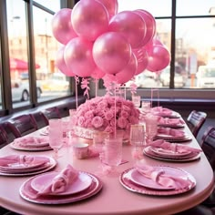 a table set with pink plates and balloons