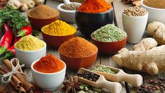 various spices and herbs in bowls on a wooden table