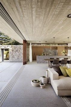 a living room filled with furniture next to a dining table and kitchen area in front of a stone wall