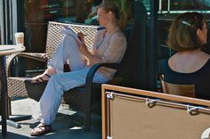 two women sitting on benches in front of a building