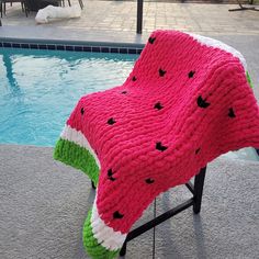 a watermelon blanket sitting on top of a chair next to a swimming pool