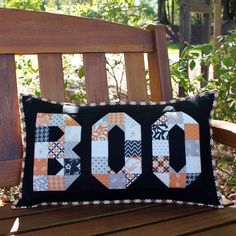 a wooden bench with a black and white quilted pillow sitting on top of it