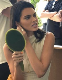 a woman is holding a hair dryer in her hand and looking at the mirror