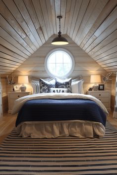 a bed in a room with a round window and wooden walls, along with two lamps on either side of the bed