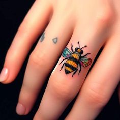 a woman's hand with a tattoo on it and a bee on the middle finger