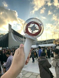 a person holding up a small object in front of a crowd at an outdoor event