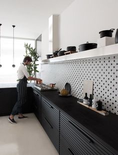 a man standing in front of a kitchen counter with pots and pans on it