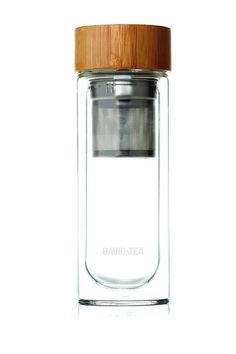 a glass bottle with a wooden lid on a white background, filled with tea infustors