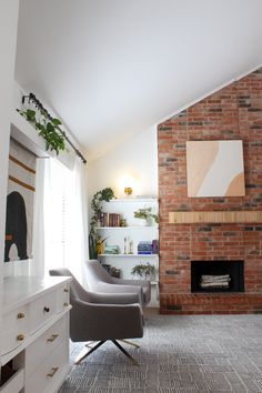 a living room with two chairs and a brick fireplace in the corner, surrounded by bookshelves