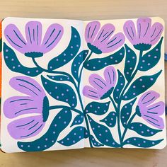 an open notebook with purple flowers and polka dots on the cover, sitting on a table