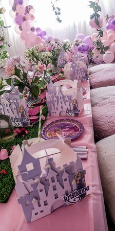 the table is set up with pink and purple balloons, paper cutouts, and princess plates