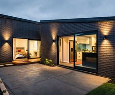 a modern house with an open patio and lights on the side of it at night