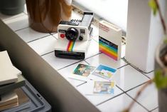 an old polaroid camera sitting on top of a counter next to some pictures and other items