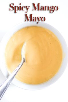 a spoon in a bowl filled with yellow sauce and the words spicy mango mayo above it