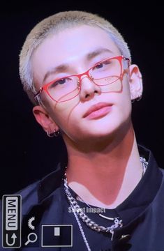 a man wearing red glasses on top of a black shirt and silver chain around his neck