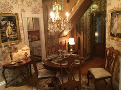 a dining room table and chairs in front of a stair case with paintings on the wall