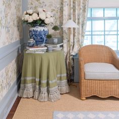 a chair and table in a room with floral wallpaper on the walls next to a window