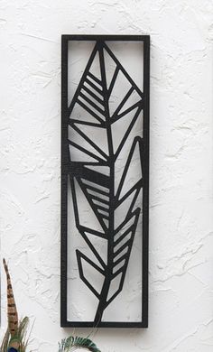 a metal sculpture on the side of a white wall next to a potted plant