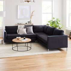 a living room with a sectional couch and coffee table on the floor in front of two windows