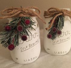 two mason jars decorated with pine needles and berries