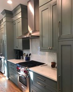 a kitchen with gray cabinets and white counter tops, stainless steel appliances and an oven