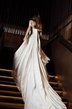 a woman in a white dress walking down some stairs