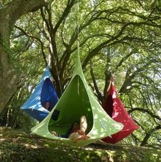 two people are sitting in tents hanging from trees