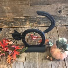 a black sculpture sitting on top of a wooden floor next to fall leaves and acorns