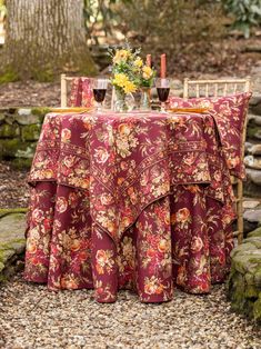 a table with two wine glasses on top of it next to some flowers and rocks