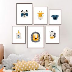 four children's art prints hanging on the wall above a bed with pillows and stuffed animals