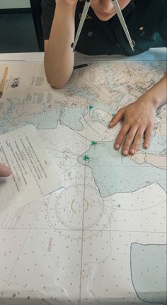 a person sitting at a table with a map and scissors in front of them,