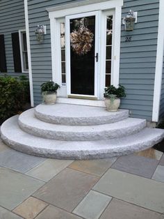 a house with steps leading to the front door and potted plants on either side