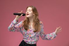 a woman singing into a microphone while holding her hands out