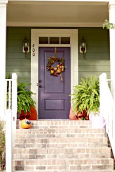 the front porch is decorated with plants and potted plants on either side of the door