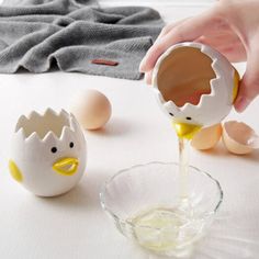 an egg being poured into a glass bowl with eggs on the table next to it