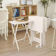 a white table and chairs in a room with wooden floors, bookshelf and potted plants