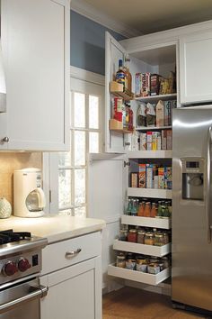 an organized pantry in the corner of a kitchen with white cabinets and stainless steel appliances