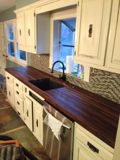 a kitchen with wooden counter tops and white cabinets