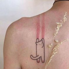 a cat tattoo on the back of a woman's upper arm and shoulder, with red string attached to it