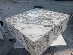 a large marble table sitting on top of a metal stand in the middle of a dirt field