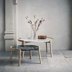 two tables with vases sitting on top of them in front of a pillar and wall