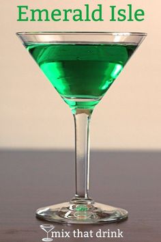 a green drink in a martini glass with the words emerald isle on it and below