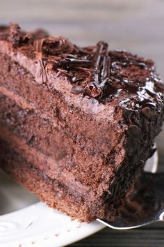 a piece of chocolate cake on a white plate with a fork in front of it