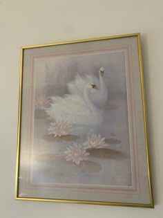 a white swan floating on top of water surrounded by lily pads in a gold frame