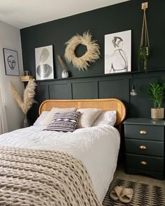 a bedroom with dark green walls, white bedding and wicker furniture in the corner