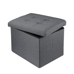 a grey ottoman with buttons on the top and bottom, sitting in front of a white background