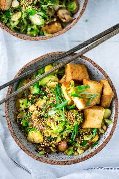 two bowls filled with tofu, broccoli and other vegetables next to chopsticks