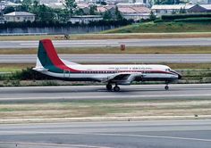 an airplane that is sitting on the tarmac near some grass and buildings in the background