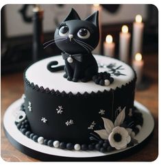 a black and white cake with a cat figurine sitting on top of it