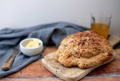 a loaf of bread sitting on top of a cutting board next to a bowl of butter